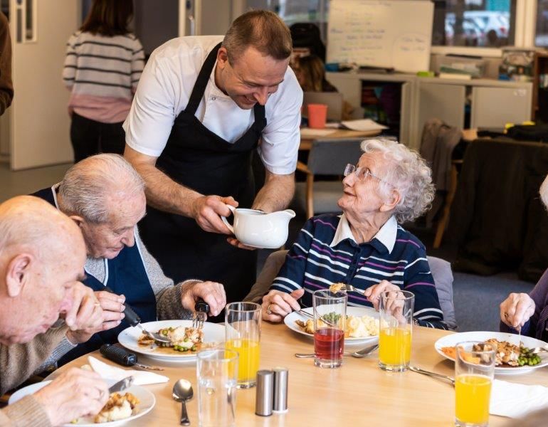 Chef pouring gravy for care home residents